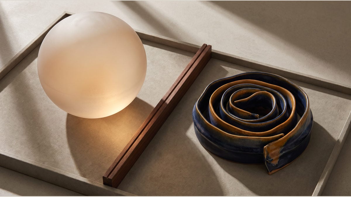 A frosted globe and a folded ceramic spiral separated by a boundary rail in an evidence tray.